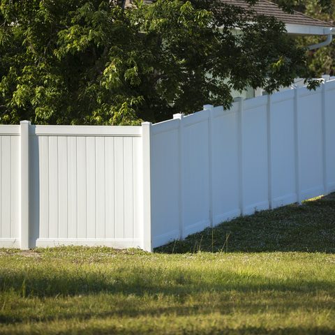 White vinyl privacy fence running along a sunny lawn