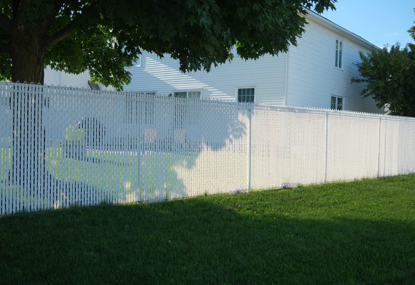 White chain link fence with privacy slats woven through the mesh