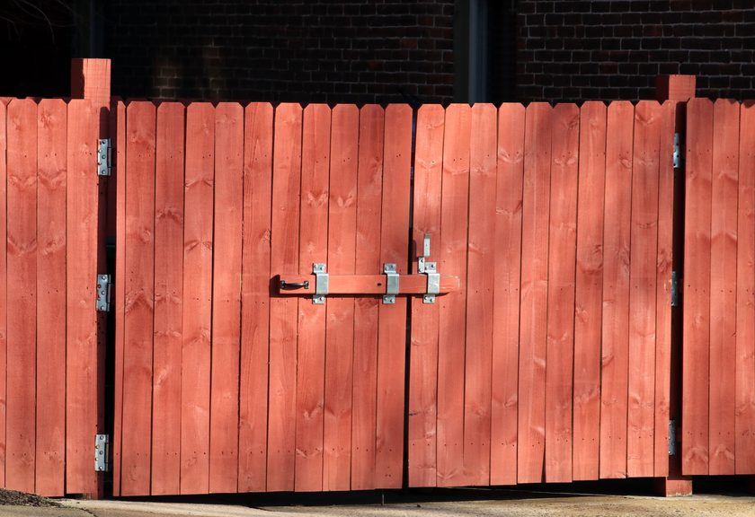 Red-stained wood double gate with a slide bolt